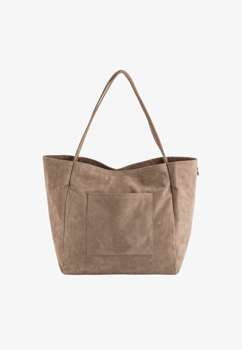 Grand sac fourre-tout en suede beige avec deux longues poignées et une poche avant. Le design a une texture douce et un dessus ouvert.