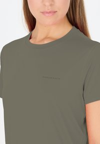 Olivgrön kortärmad träningsskjorta i andningsbart material. Har rundad halsringning och texten 'ENDURANCE' i en diskret tryck.