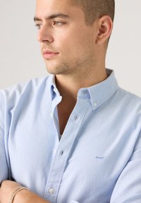  Lichtblauw button-up shirt van katoen, met een klassieke kraag, witte knopen en een klein Levi's logo op de borst.
