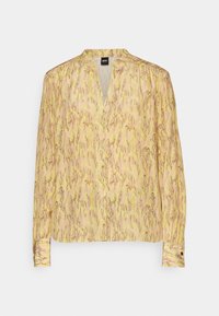 Long-sleeve blouse in pale yellow with a snake print pattern in gold and brown. Features a V-neck and buttoned cuffs. Lightweight fabric.