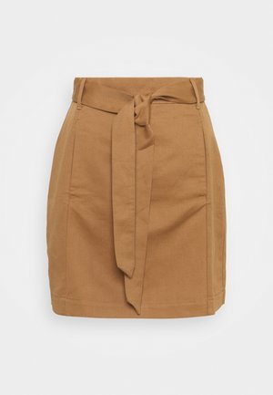 Jupe mini beige cintrée en tissu texturé. Elle présente des poches latérales et un lien à la taille, avec une coupe ajustée et un ourlet droit.