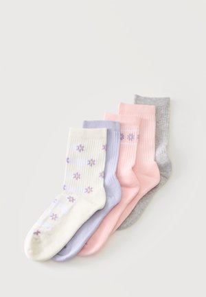 Fem par ribstrikkede sokker i hvid med lilla blomster, lys lilla, to pink par - en med blomstermønster - og et gråt par, lagt i række.