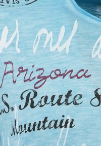 Tela de color azul claro con diferentes estilos y colores de texto, incluyendo blanco y burdeos, presentando palabras como "Arizona" y "Ruta 87."
