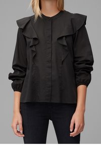 Black blouse featuring a buttoned front, ruffled collar, and elasticized cuffs. Made from a smooth fabric, with a loose fit and no visible patterns.