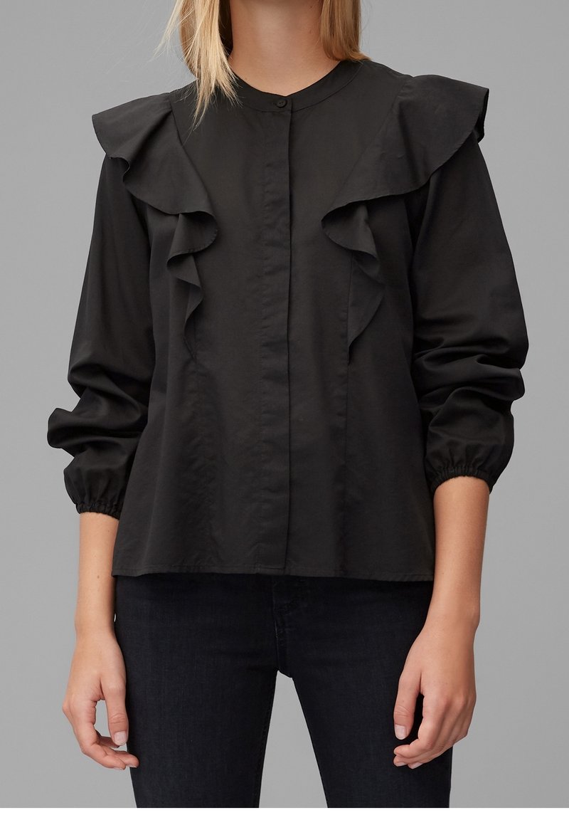 Black blouse featuring a buttoned front, ruffled collar, and elasticized cuffs. Made from a smooth fabric, with a loose fit and no visible patterns.