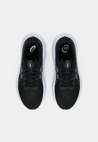 Zwarte sportschoenen met een geperforeerde mesh bovenkant, witte zool en zwarte veters. Voorzien van logo-accenten op de tong en inlegzool.