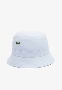 Gorra de cubo azul claro hecha de tela texturizada, con un logo de cocodrilo verde bordado en el lateral y un ala ancha y flexible.