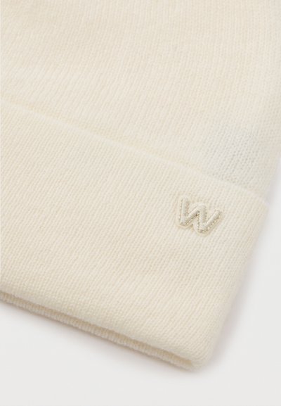 Krém színű kötött gyapjú sapka hajtott szegéllyel, a szegély szélén egy kis hímzett "W" logóval.