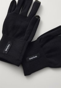Schwarze Handschuhe aus strukturiertem Stoff, die enganliegend sind und mit GripGrab-Labels an den Bündchen versehen sind, sowie mit touchscreen-kompatiblen Fingerspitzen.