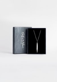 Silverhängehalsband med avlång, avsmalnande design, hängande på en delikat kedja, presenterat i en strukturerad svart smyckesask.