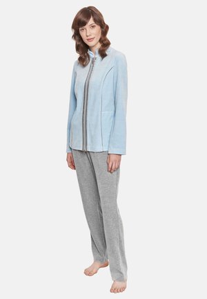 Light blue zip-up jacket with a high collar, gray sweatpants, and bare feet. The jacket features a smooth texture and contrasting seams.