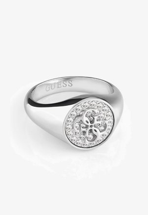 Bague chevalière Guess en argent avec visage rond orné de cristaux clairs et logo G entrelacé, anneau poli et lisse.