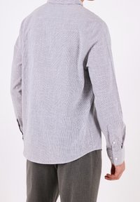 Långärmad skjorta med knappar i ljusgrått med tunna vita ränder. Har en krage, rundad fåll och knäppärmar. Mjuk, strukturerad tyg.