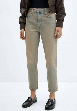 Person wearing faded straight-leg beige jeans paired with black loafers and a brown bomber jacket with ribbed cuffs.