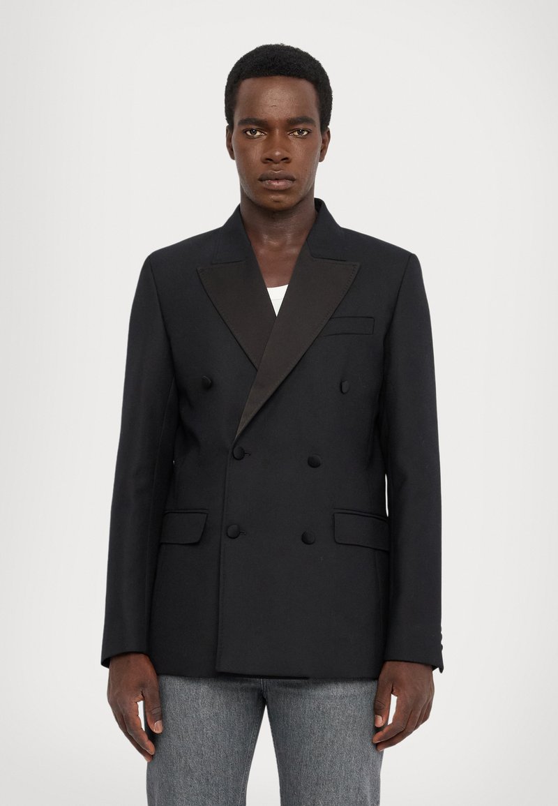 Dubbelzijdige zwarte blazer met satijnen revers, voorzakken en gedetailleerde knopen. Gemaakt van een soepele stof, biedt een getailleerde pasvorm.
