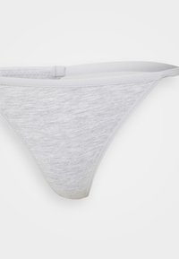 Fio dental de algodão cinza claro com uma textura suave, apresentando uma cintura fina e um design minimalista. Sem padrões ou adornos visíveis.