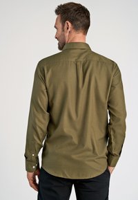 Olivgrünes Langarmhemd mit glatter, strukturiertem Stoff, Knopfmanschetten und einem Rückenfalten, samt abgerundetem Saum.