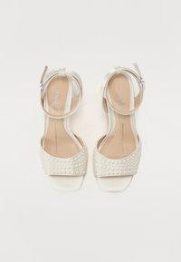 Λευκές σατέν ψηλοτάκουνες σανδάλες με φαρδύ λουρί διακοσμημένο με πέρλες και λεπτό λουρί στον αστράγαλο που διαθέτει ασημένια αγκράφα.