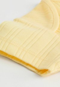 Dzeltena ribota auduma ar mīkstu tekstūru un elastīgām malām, ar smalkām vertikālām svītrām un salocītu dizainu.