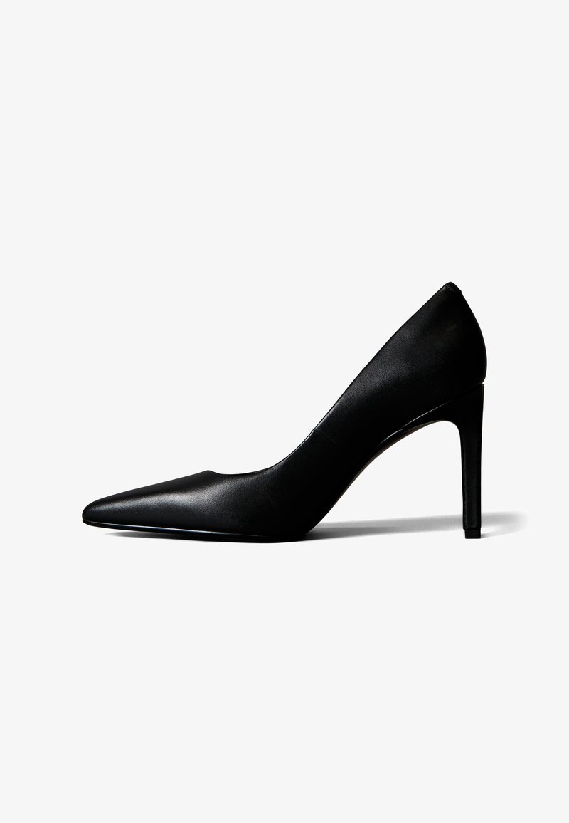 Chaussure à talon haut en cuir noir à bout pointu avec un talon fin, vue de profil sur fond blanc.