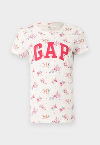 T-shirt blanc à manches courtes avec un petit imprimé floral coloré et un grand logo rouge GAP sur la poitrine.