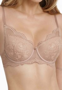 Bügel-BH aus zartem Beige mit Spitzenverzierungen, gewellten Kanten, floralen Mustern und einem Mittelbogen. Verstellbare Träger und strukturierte Cups.