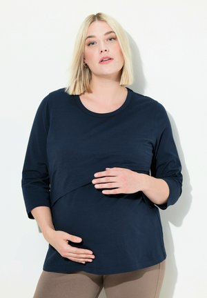 Dunkelbluse Umstandshirt mit Dreiviertelärmeln und rundem Ausschnitt. Weicher, dehnbarer Stoff mit einem geschichteten Design auf der Vorderseite.