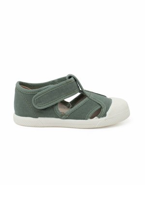 Grüner Canvas-Schuh mit einer weißen Gummisohle, mit ausgeschnittenen Seiten und einem Klettverschluss über dem Spann für einen sicheren Sitz.