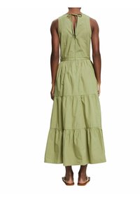 Robe maxi en coton vert clair. Dotée d'un col rond, d'un dos ouvert avec fermeture à nouer, et d'une jupe à volants avec des détails froncés.