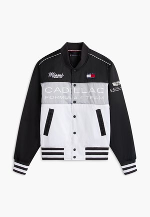 Czarna, szara i biała kurtka zespołu Formuły 1 Cadillac z logo Miami i Tommy Hilfiger, z paskowanymi mankietami i zapięciem na zatrzaski z przodu.