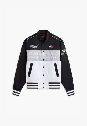 Must, hall ja valge Cadillac Formula 1 meeskonna jakk Miami ja Tommy Hilfigeri logodega, triibuliste mansettide ja trukknappidega ees.