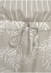 Lichtgrijze stof met witte strepen en een bladpatroon. Kenmerken zijn een gathered taille en strikdetail. Soepele textuur.