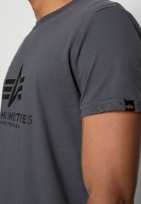 Gray short-sleeve t-shirt with a round neckline, featuring a black graphic design on the front and a small branded label on the sleeve.