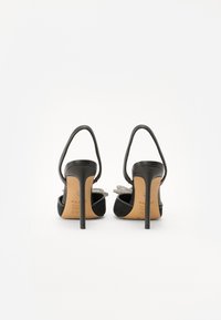 Sandales à talons hauts noires avec un design épuré, dotées d'une bride arrière, d'accents en cristal et d'une texture en cuir lisse sur le dessus.