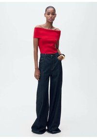 Rode off-the-shoulder top gecombineerd met hoogrendement donkere wijde jeans; zachte textuur, casual pasvorm en minimale details.