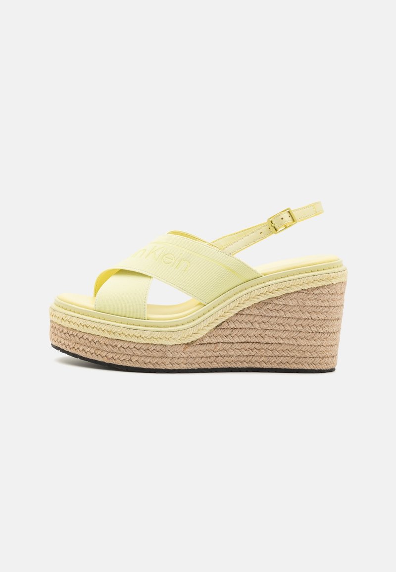 Sandales compensées jaunes à plateforme avec design à brides croisées, en matériau élastique ; détails en jute tressé sur la semelle compensée ; bride de cheville ajustable.
