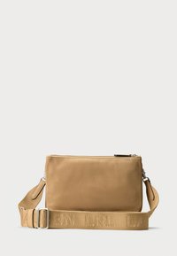 Sac bandoulière beige en tissu lisse, avec fermeture zippée et une bandoulière texturée avec lettrage en relief. Forme rectangulaire, design minimaliste.