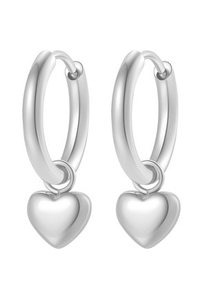 Zilveren oorringen met gladde, hartvormige hangers die aan elke oorring hangen, afgebeeld tegen een witte achtergrond.