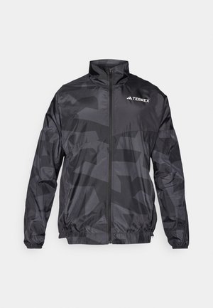 Black lightweight windbreaker jacket with a matte finish, zip closure, high collar, and subtle geometric pattern. Features Terrex logo.