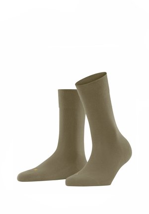 Olivgrüne Baumwollsocken mit glatter Textur, mittlerer Schafthöhe und dezentem geripptem Bündchen. Mit einem kleinen gelben Logo auf der Fußspitze.