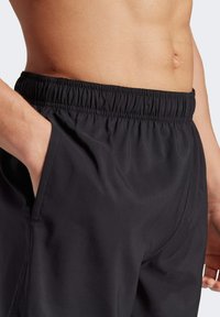 Black shorts with a stretchy waistband, featuring a side pocket. Material appears smooth with a lightweight, breathable texture.