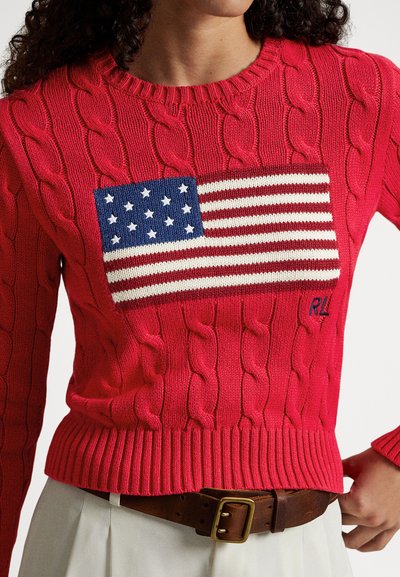 Pulover roșu cu model tricotat, având un dreptunghi albastru cu stele albe și dungi orizontale. Guler și tiv cu margine nervurată; marcă "RL".