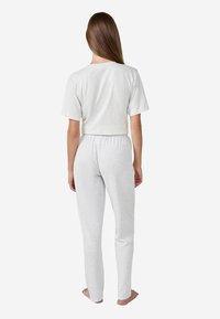 Grijze katoenen shirt met korte mouwen en een outfit met aansluitende broek. Gladde textuur met een relaxte pasvorm. Elastische tailleband op de broek, enkellang.