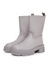 Botas de tobillo con suela gruesa, fabricadas en suave cuero gris con punta redondeada y costuras mínimas. Cuentan con tiradores para facilitar el calzado.