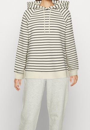 Un hoodie rayé en blanc cassé et noir, avec une capuche à cordon, des manches raglan et une coupe décontractée. Assorti à un pantalon de survêtement gris clair.