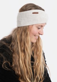 Skręcony, biały, dziany opaska na głowę, ozdobiona brązową skórzaną metką. Miękka tekstura i szeroki kształt zapewniają ciepło.