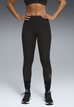 Leggings neri a vita alta con un design elegante e una texture liscia, abbinati a scarpe nere e bianche con un accento menta.