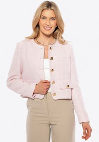Světle růžová tweedová bunda s cropped střih, strukturovaným fit a zlatými knoflíky, a malou přední kapsou. Stylová přes bílý top.