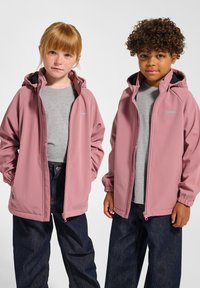 Zwei Kinder tragen leichte, mit Reißverschluss versehene Kapuzenjacken in sanftem Rosa, kombiniert mit grauen T-Shirts und dunkelblauen Jeans.
