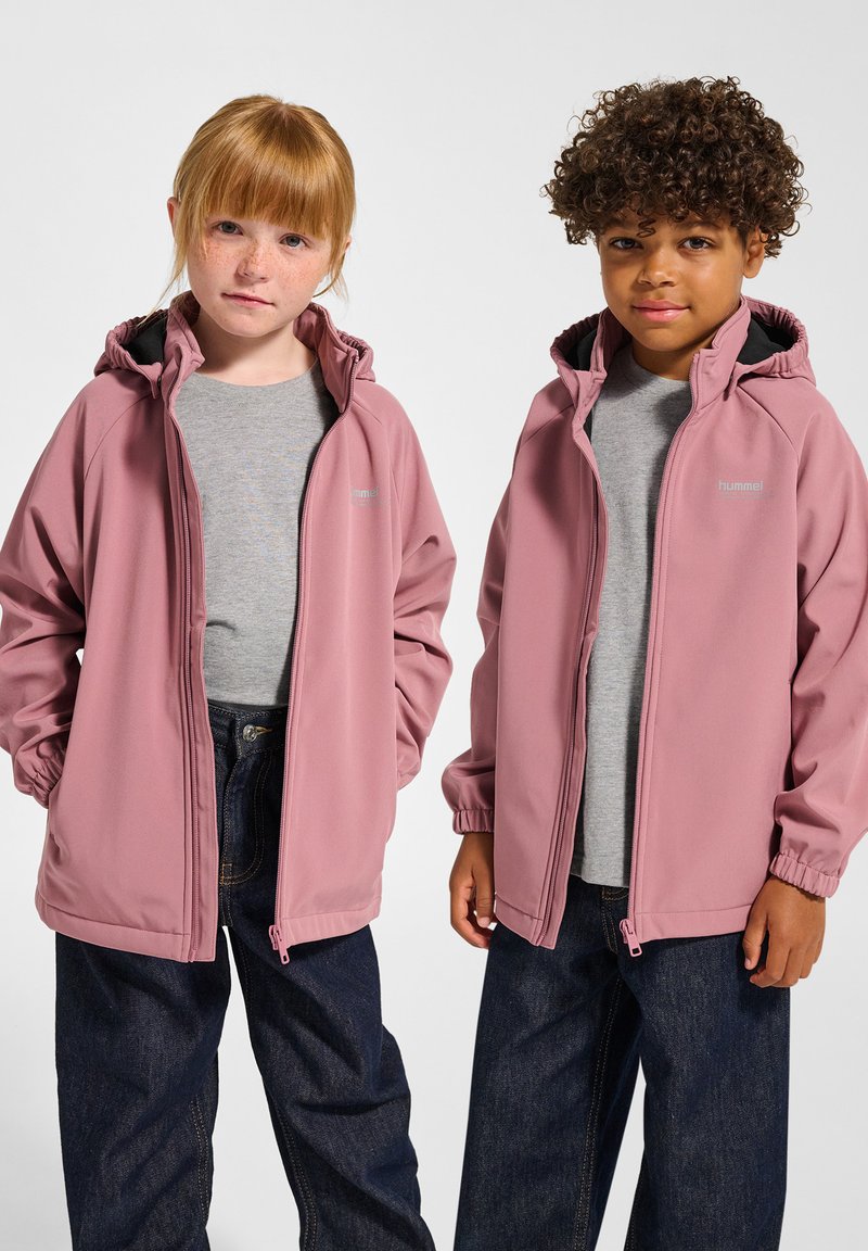 Zwei Kinder tragen leichte, mit Reißverschluss versehene Kapuzenjacken in sanftem Rosa, kombiniert mit grauen T-Shirts und dunkelblauen Jeans.
